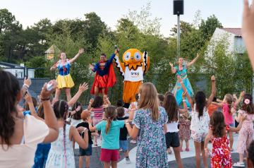 Soirée Soly Disco au camping Le Vieux Port dans les Landes, avec enfants et adultes dansant sous des lumières colorées et une ambiance festive en plein air, à proximité du parc aquatique et de l’océan Atlantique, sous un ciel bientôt étoilé.