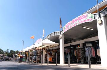 Commerces du camping Le Vieux Port dans les Landes, avec supermarché SPAR proposant alimentation, baguettes et viennoiseries artisanales, librairie-presse, boutiques d’articles de plage et souvenirs, ainsi que snacks et bars à côté du parc aquatique, offrant tout le nécessaire à proximité immédiate des hébergements en bord de mer.