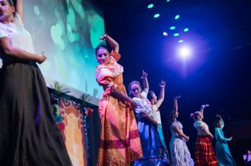 Spectacle Encanto à l’Arena du camping Le Vieux Port, présenté par les animateurs du camping, retraçant l’univers magique de la famille Madrigal avec des chorégraphies dynamiques, des voix off entraînantes et une mise en scène immersive. Les animateurs portent des costumes colorés et évoluent sur une scène éclairée par des jeux de lumière sophistiqués, captivant un public familial enthousiaste venu vivre un voyage musical enchanteur mêlant émotions, magie et convivialité.