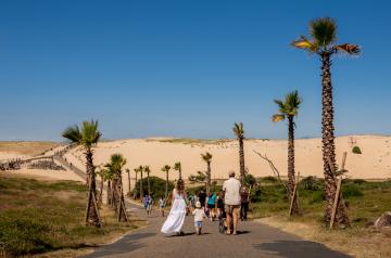 Une famille vue de dos est sur le chemin sécurisé qui mène directement à la plage depuis leur lieu de résidence de vacances. Cela évoque la simplicité d'avoir tous les services et points d'intérêts à portée.