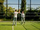 Joueurs au terrain de padel du camping des Landes qui se tapent les mains en signe de convivialité lors de leurs vacances en bord de mer dans une location tout équipée avec infrastructures de qualité
