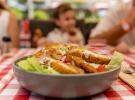 flou d'une famille à table avec au 1er plan une salade césar très joliment préparée à la brasserie VP du camping avec restaurants des Landes 5 étoiles