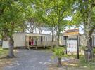 Visite guidée d’un mobil-home moderne sur un camping familial, montrant l’intérieur lumineux avec salon, cuisine et terrasse extérieure en bois, destinée aux futurs propriétaires souhaitant investir dans une résidence de vacances