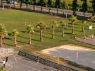 Vue panoramique de la plaine des sports du camping Le Vieux Port, avec terrains de football et de volley-ball en herbe, entourés d'arbres verts et de zones de détente, offrant un espace convivial pour les activités sportives et récréatives en plein air