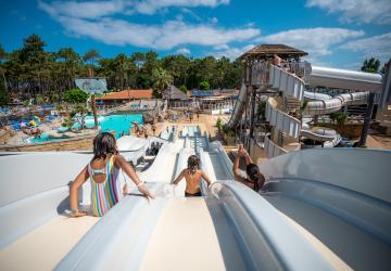Enfants dévalant les pentes du toboggans au parc aquatique du camping 5 étoiles Le Vieux Port dans les Landes