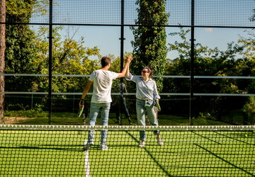 Joueurs au terrain de padel du camping des Landes qui se tapent les mains en signe de convivialité lors de leurs vacances en bord de mer dans une location tout équipée avec infrastructures de qualité
