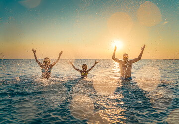 famille heureuse dans l'océan au sunset en train de jeter de l'eau avec paillette pour les fêtes de fin d'année 2024 et annoncer 2025 Le Vieux Port article 2025 Découvrez la Wishlist  la nouvelle fonctionnalité du camping 5 Le Vieux Port La magie des vacances de Noël et des fête de fin d'année sauvegarder séjour camping