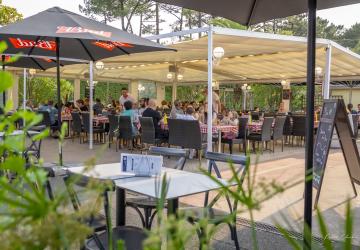 vision depuis la végétation sur une table disponible avec la carte ou menu disposée sur la surface avec au fond les tablées remplies au restaurant de la brasserie du VP