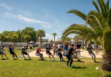 Personnes faisant du tir à la corde sur le terrain multi sport de leur lieu d'accueil au camping dans les Landes par temps ensoleillé