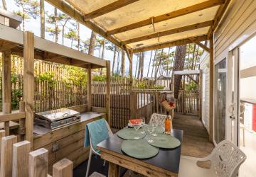 Plancha individuelle moderne et barbecue collectif en plein air au meilleur camping des Landes en bord de mer, installés sur une terrasse conviviale entourée de pins, offrant aux vacanciers un espace agréable pour cuisiner et partager des repas en famille ou entre amis.