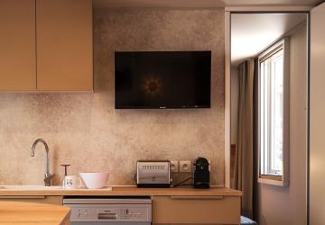 Photo d'une télévision écran plat moderne installée dans le salon du mobil home Lodge Premium 4 personnes, modèle Taos, situé au camping Le Vieux Port à Messanges. La télévision est fixée au mur face à un canapé confortablement aménagé, avec une décoration chaleureuse et lumineuse dans un espace convivial. La pièce dispose également d'éléments de mobilier en bois clair, d'une grande fenêtre laissant entrer la lumière naturelle, et d'accessoires modernes pour un séjour agréable en famille ou entre amis