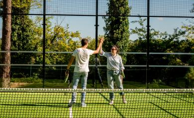 Joueurs au terrain de padel du camping des Landes qui se tapent les mains en signe de convivialité lors de leurs vacances en bord de mer dans une location tout équipée avec infrastructures de qualité