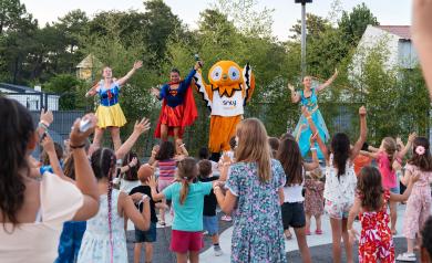 Soirée Soly Disco au camping Le Vieux Port dans les Landes, avec enfants et adultes dansant sous des lumières colorées et une ambiance festive en plein air, à proximité du parc aquatique et de l’océan Atlantique, sous un ciel bientôt étoilé.