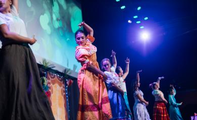 Spectacle Encanto à l’Arena du camping Le Vieux Port, présenté par les animateurs du camping, retraçant l’univers magique de la famille Madrigal avec des chorégraphies dynamiques, des voix off entraînantes et une mise en scène immersive. Les animateurs portent des costumes colorés et évoluent sur une scène éclairée par des jeux de lumière sophistiqués, captivant un public familial enthousiaste venu vivre un voyage musical enchanteur mêlant émotions, magie et convivialité.