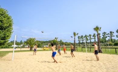 Des personnes jouant au beach-volley sur un terrain sablonneux avec un filet tendu entre deux poteaux. Plusieurs joueurs en tenues de sport légères participent activement au match, certains sautant pour smasher la balle tandis que d'autres se préparent à la réception. Le terrain est délimité par des lignes blanches sur le sable fin, avec un ciel bleu en arrière-plan et une ambiance ensoleillée typique d’une journée estivale parfaite pour ce sport de plage convivial et dynamique. Jeu favorisant coopération.