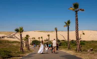Une famille vue de dos est sur le chemin sécurisé qui mène directement à la plage depuis leur lieu de résidence de vacances. Cela évoque la simplicité d'avoir tous les services et points d'intérêts à portée.