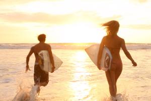Camping dans les Landes avec un environnement exceptionnel (2) Un paradis pour les activités sportives dans les Landes avec surfeurs qui courrent dans l'océan avec leurs planches au sunset