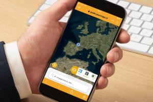 homme d'affaire business en costume cravate qui tient son smartphone dans sa main gauche et qui visualise la localisation gps de ses prochaines vacances dans le sud ouest FR