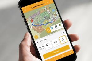 personne tenant dans sa main son téléphone mobile avec le guidage interactif de l'application RESASOL ouvert pour pouvoir se repérer dans le camping pendant ses vacances
