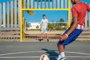 Camping avec City Stade dans les Landes en bord de mer (6) gros plan sur les chaussures basket d'une jeune homme qui s'apprête à taper dans la balle pour réaliser un but dans la cage de son ami