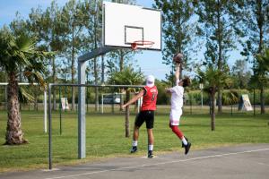Camping avec terrain de basket dans les Landes en bord de mer Joueur de basket en pleine action lors d’un match au camping
