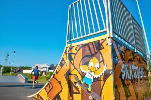 Enfants s'amusant dans le skatepark du camping entouré de verdure, Jeunes skateurs utilisant le skatepark du camping au bord de la forêt