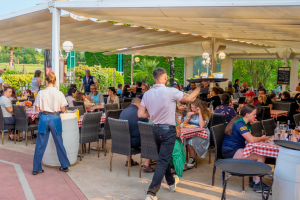 brasserie du camping en plein rush de restauration avec serveur qui tiennent le plateau des commandes à une main par un temps ensoleillé de fin de printemps début d'été