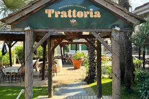 devanture de la trattoria pour les plats italiens avec vue sur la terrasse et la verdure de ce restaurant italien à côté du parc aquatique et des transats bleus