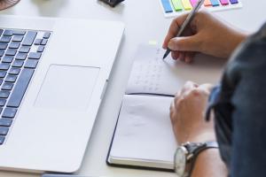 femme-ecriture-cahier-table-ordinateur-portable-equipements