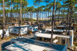 All-inclusive-services-camping-5-etoiles-vieux-port-landes-quartier-premium-vue drone du haut des toits des mobil homes par beau temps ensoleillé avec la pinède et la vue sur la dune derrière l'océan