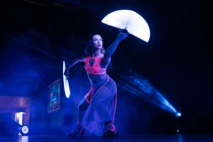 Spectacle des contes lumineux de SPACE WESTERN sur fond noir et violet avec l'éventail d'une geisha cyberpunk grâce à la colororimétrie fluorescente du rose et des LEDs de ses accessoires