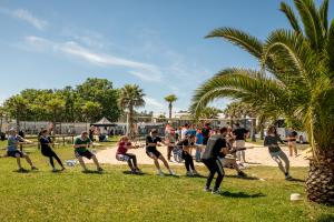 Personnes faisant du tir à la corde sur le terrain multi sport de leur lieu d'accueil au camping dans les Landes par temps ensoleillé