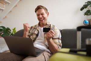 portrait-d-un-homme-en-vacances-regardant-sa-carte-de-credit-achetant-des-billets-en-ligne-reservant-un-camping
