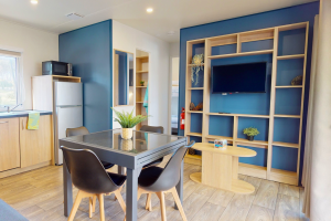 Téléviseur à écran plat de 40 pouces installé dans le salon du mobil-home, avec un meuble en bois clair et une télécommande à côté