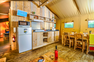 Vue du téléviseur fixé au mur dans la salle de séjour de la tente cosy, avec un écran montrant un programme de vacances ou d’activités du camping
