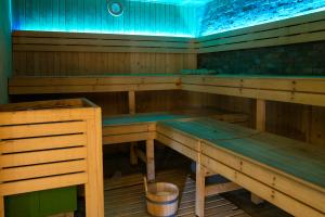 Vue de l’intérieur d’un sauna moderne vide, entièrement réalisé en bois clair avec bancs superposés, ambiance chaude et épurée, lumière tamisée invitant à la détente, aucune personne présente, atmosphère zen et sereine.