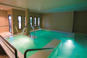Espace aquatique intérieur d’un spa moderne avec bassins d’eau claire, mettant en avant plusieurs bras de jets d’eau puissants et orientables projetant des cascades d’eau apaisantes, créant une ambiance relaxante dans un cadre lumineux et épuré
