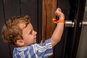 Enfant souriant ouvre la porte du mobil-home avec son bracelet à puce NoKey Service au camping Le Vieux Port
