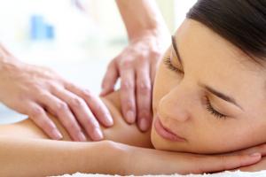 Photo massage corps détente spa : thérapeute effleurages longs modelage suédois dos lombaires jambes, huile chaude chandelle, position ventre relaxation profonde anti-stress.