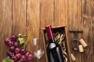 Photo vue aérienne support bois raison rouge : verre vin vide élégant, bouteille sans étiquette, tire-bouchon professionnel, bouchons liège, composition oenologique classieux.