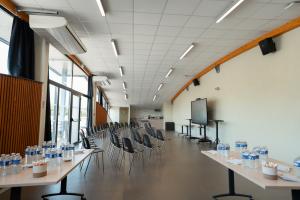 Salle de l’Annexe du Vieux Port aménagée en amphithéâtre : chaises face à un écran, tables avec bouteilles d’eau et mini-bar avec coin café cosy pour réunions et séminaires.