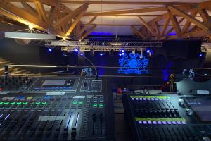 Vue depuis la régie avec la table de mixage professionnelle et logo d'entreprise en toile de fond