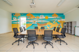 Salle du mini-club du camping Le Vieux Port aménagée pour un groupe d’environ 10 personnes : espace de réunion avec vidéoprojecteur, écran et mobilier modulable.