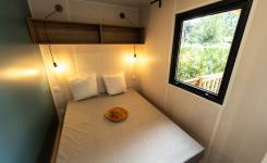 Lit double pour deux personnes Intérieur Cabane Bois 4 personnes du camping 5 étoiles Le Vieux Port à Messanges Vieux Boucau dans les Landes avec chapeau sur le lit