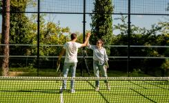Joueurs au terrain de padel du camping des Landes qui se tapent les mains en signe de convivialité lors de leurs vacances en bord de mer dans une location tout équipée avec infrastructures de qualité