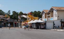 Commerces-services-camping-5-etoiles-vieux-port-landes-boutiques-velos-pour-acheter-tous-les-objets-de-plage-et-autres-souvenirs-de-vacances-dans-les-landes-en-bord-de-mer-avec-des-jeunes-personnes-qui-marchent-sur-la-place-du-village-vers-leur-location-de-vélos