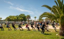 Personnes faisant du tir à la corde sur le terrain multi sport de leur lieu d'accueil au camping dans les Landes par temps ensoleillé