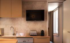 Photo d'une télévision écran plat moderne installée dans le salon du mobil home Lodge Premium 4 personnes, modèle Taos, situé au camping Le Vieux Port à Messanges. La télévision est fixée au mur face à un canapé confortablement aménagé, avec une décoration chaleureuse et lumineuse dans un espace convivial. La pièce dispose également d'éléments de mobilier en bois clair, d'une grande fenêtre laissant entrer la lumière naturelle, et d'accessoires modernes pour un séjour agréable en famille ou entre amis