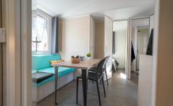 Séjour du mobil-home Resasol avec table, assises et canapé convertible pour deux personnes