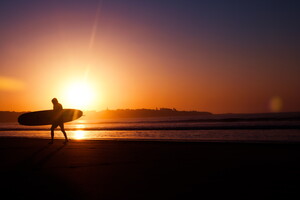 Surfeur au coucher de soleil sur une plage des Landes au coucher de soleil